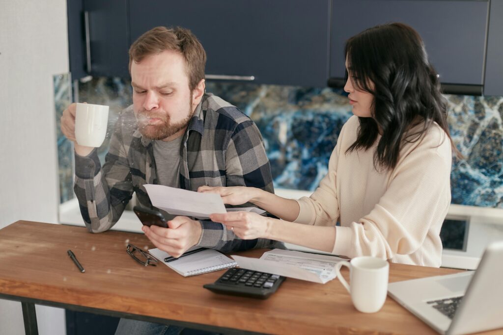 Couple discussing financial documents and budgeting at a kitchen table.
